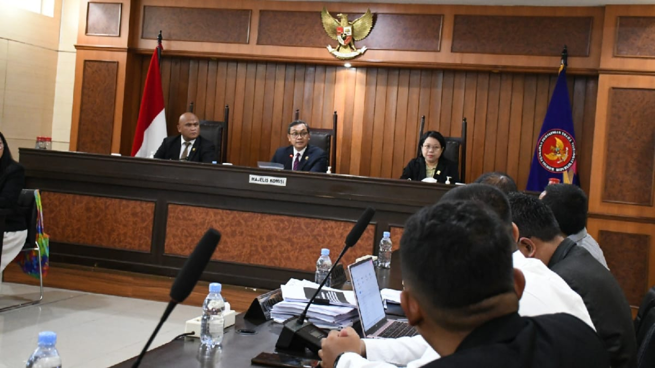 Suasana persidangan di Gedung KPPU, Jakarta. Tiga anggota Majelis Komisi terlihat duduk di meja persidangan, sementara pihak terkait mengikuti jalannya pemeriksaan dari meja di hadapan majelis.